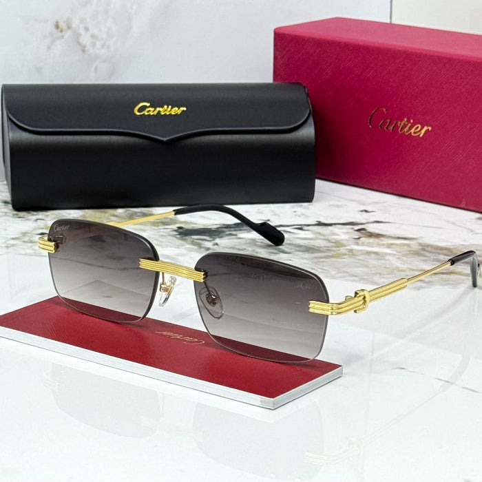 Cartier rimless sunglasses with gold metal frames and dark gray gradient lenses, displayed on a red stand with the black hard case and pink Cartier box behind on a white marble surface.